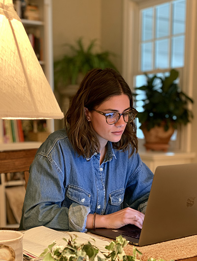 A female author sitting at her laptop in her home office.