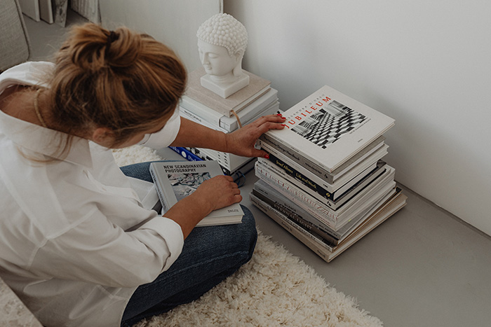 A woman sitting and looking through a pile of books.